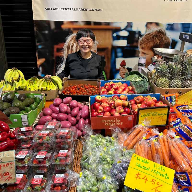 Woman in front of fresh produce fruits and vegetables