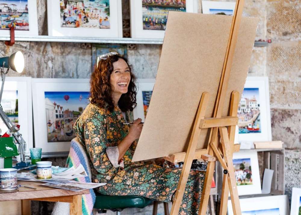 woman smiling while sitting and painting