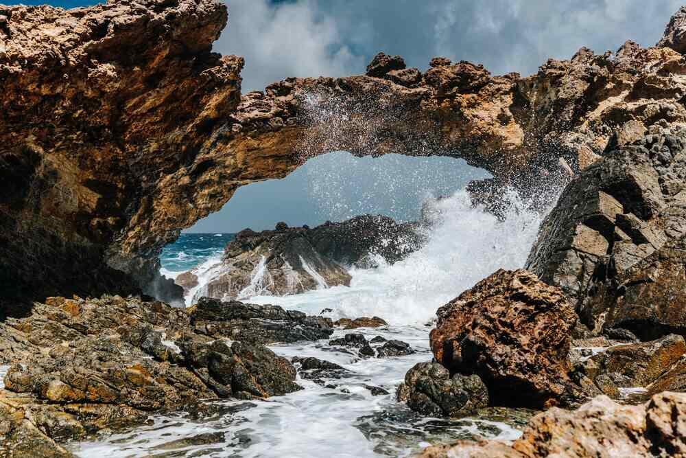 Aruba's iconic Natural Bridge made of rocks with ranging beach