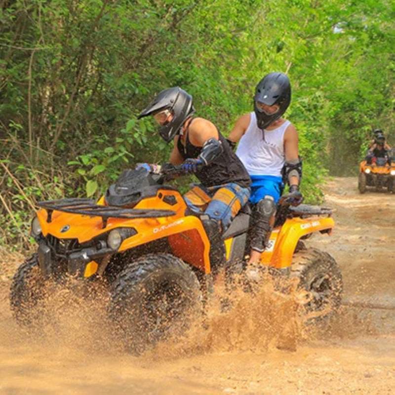 riding orange ATV in a muddy road surrounded by trees