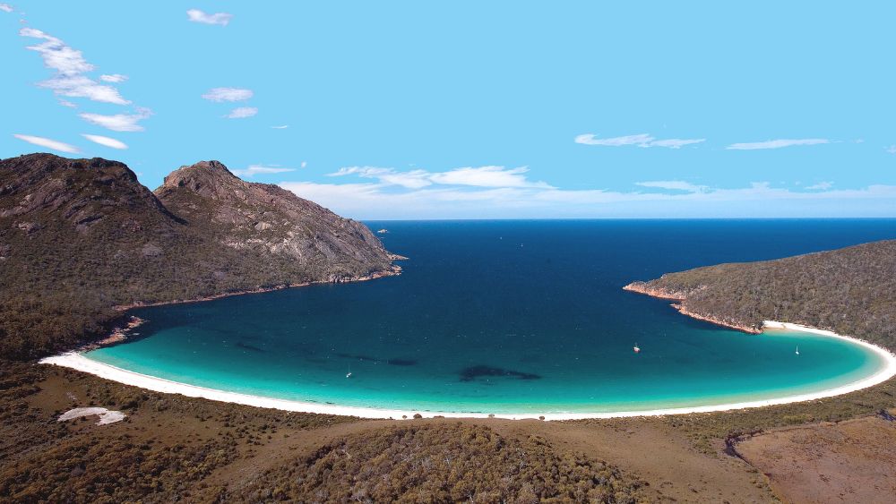 green-blue body of water surrounded by brown hill