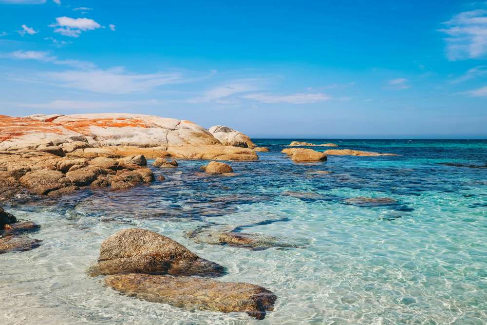 rock formation with orange color on top near the crystal-clear waters