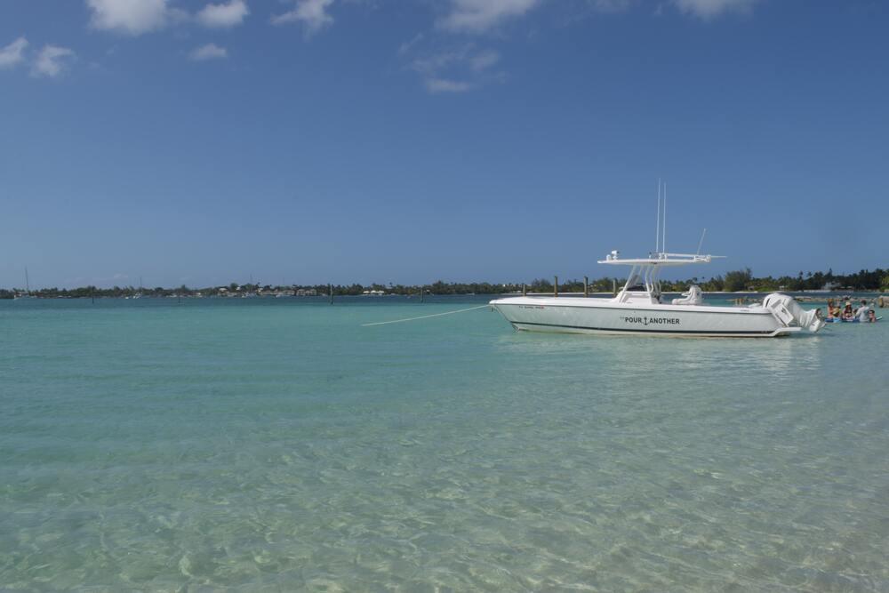 yatch floating in a clear water with people swimming on the side at Jaws beach
