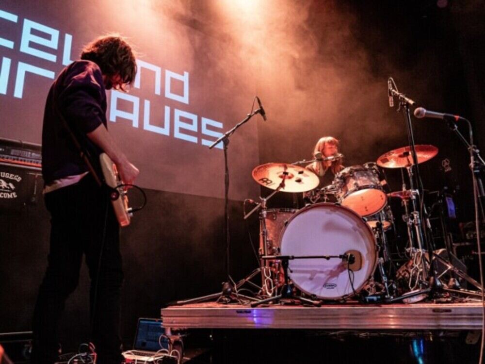 Band playing guitar and drums while singing on stage
