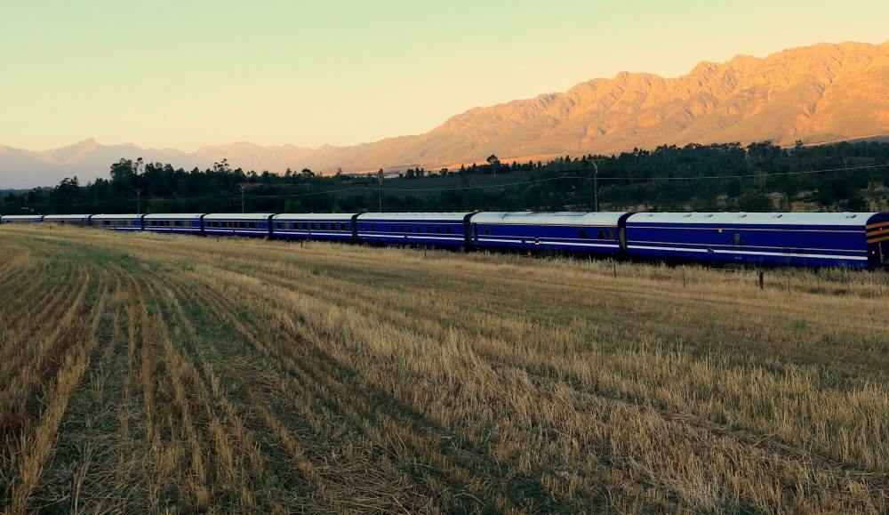 blue train passing by the field
