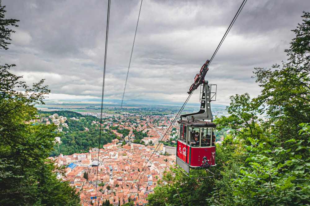 red cable car on top showing city view with buildings and houses- romania digital nomad visa