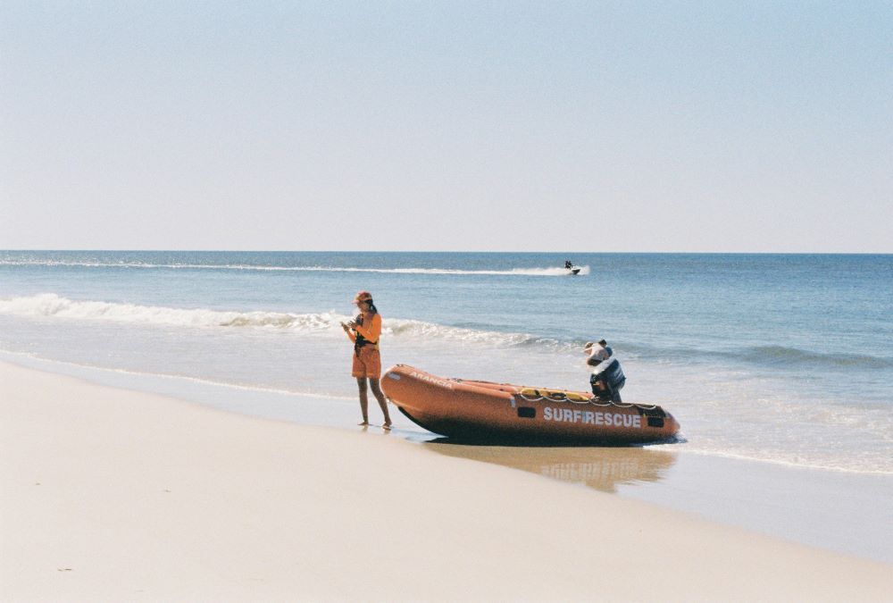 a woman standing beside a raft boat near the ocean