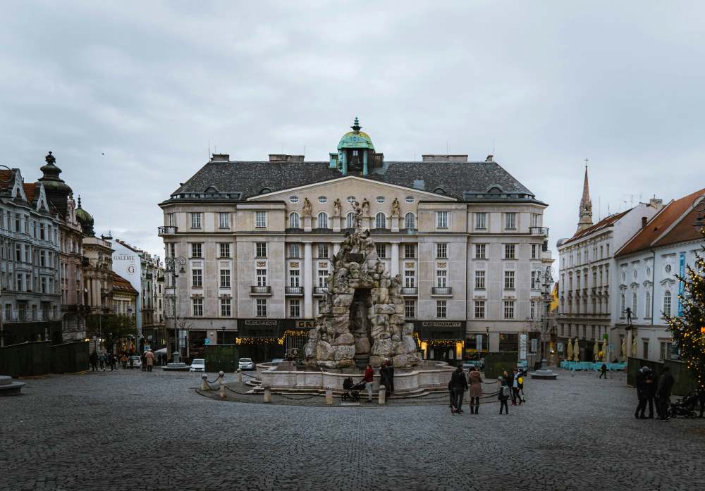 people walking and sitting near the fountain in the middle of a park like street- czech republic digital nomad visa