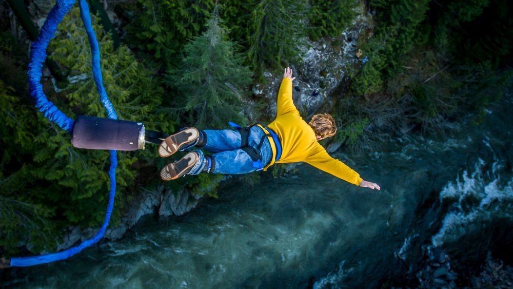 man in yellow sweatshirt bungee jumping at the river - reasons to visit australia