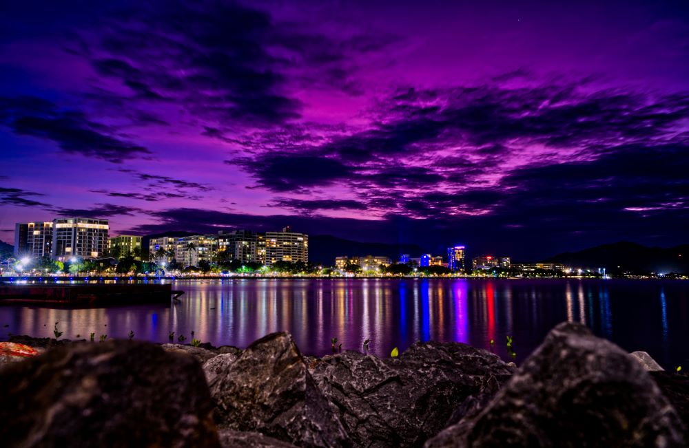 buildings and community showing city lights in front is the body of water during night time