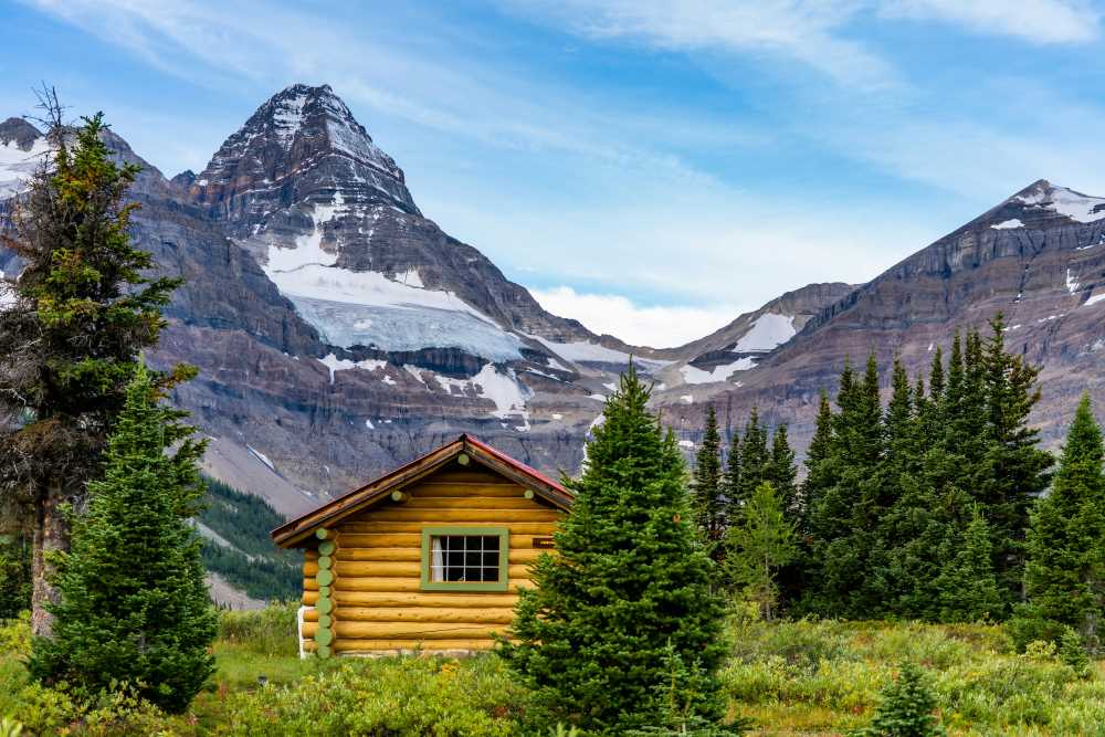 yellow wooden house in middle of the mountain and green trees