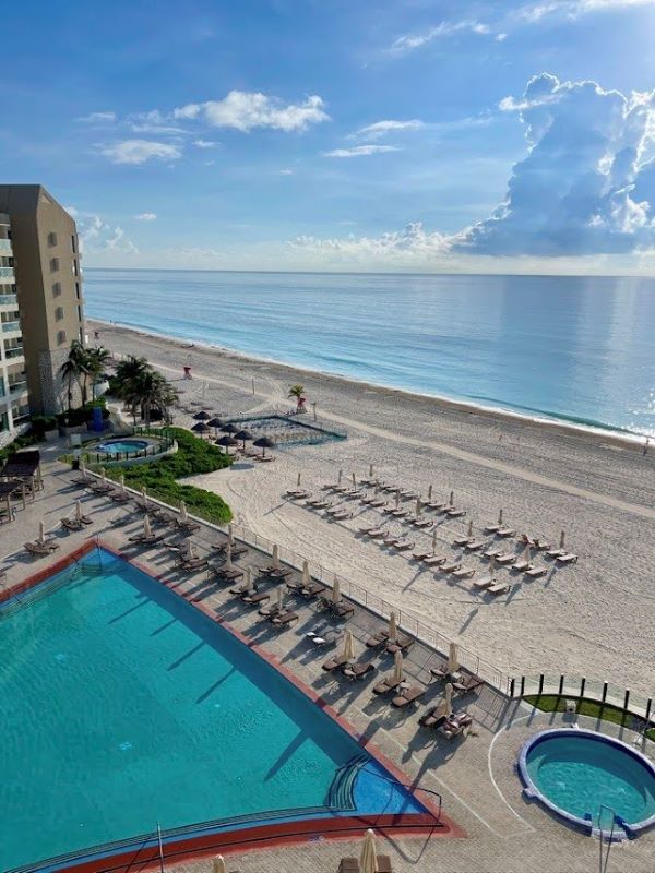 view from our room showing empty beach beds and swimming pools in front of the beach - Best Time to Visit Cancun