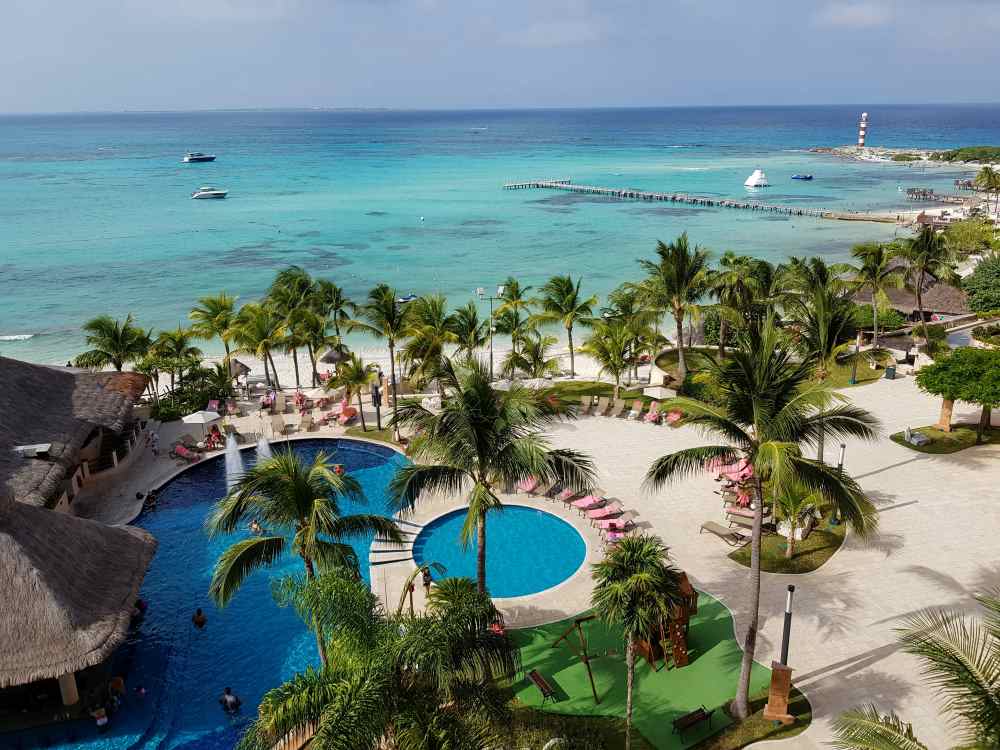 aerial view of the hotel with pool surrounded by palm trees near the beach