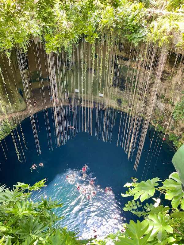 top view of cenotes with people swimming in it - Best Time to Visit Cancun
