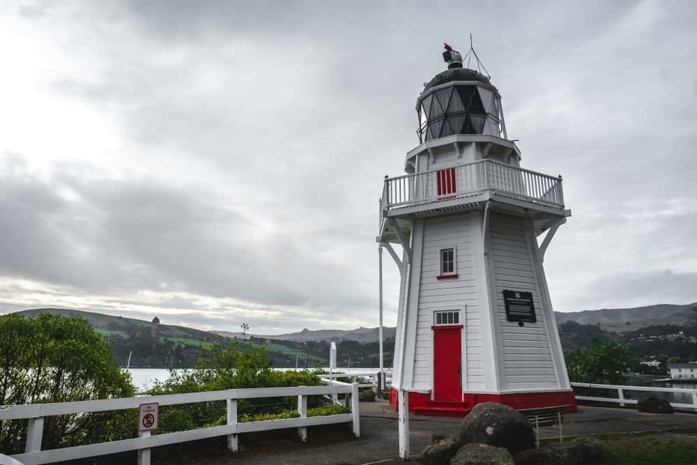 white and red lighthouse in the top near body of water