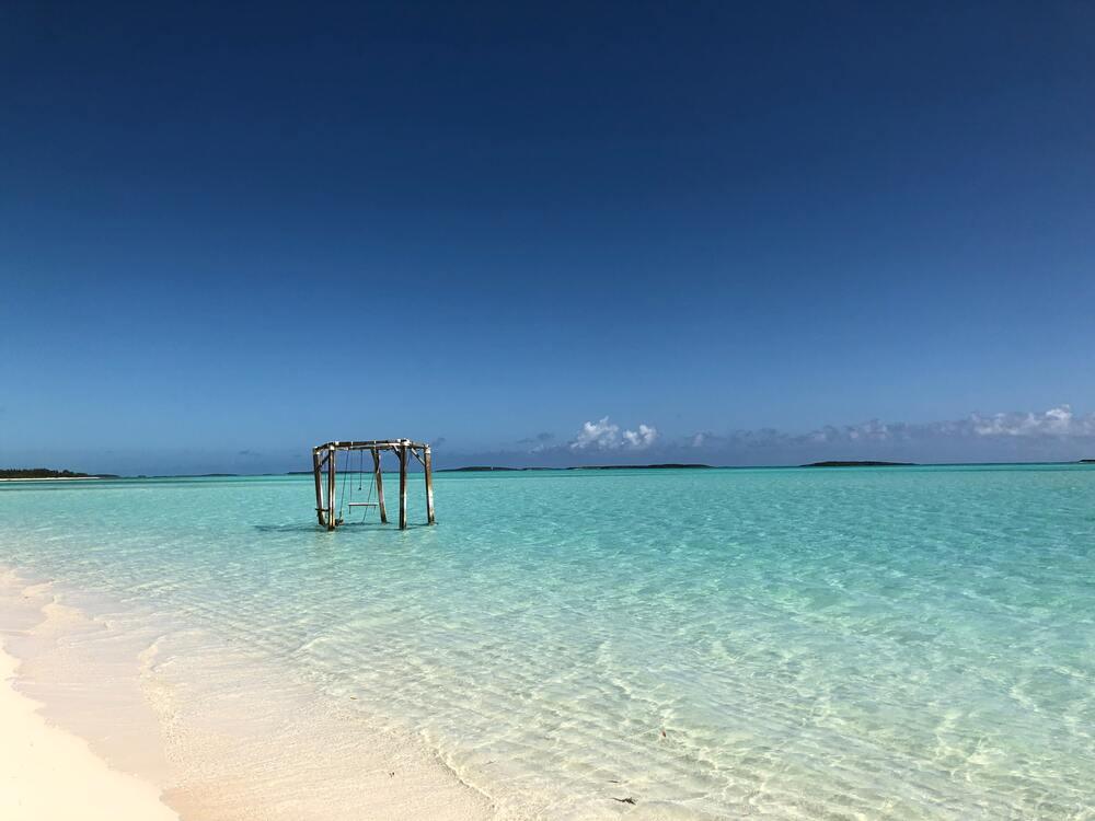 Wooden Gazebo at the seashore of a stunning vista of white sand and crystal-clear turquoise waters at Coco Plum Beach Bahamas