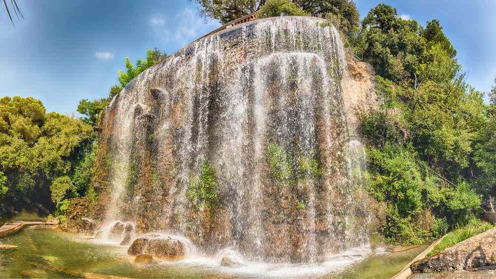 waterfall in a rock hill surrounded by green plants and trees- Things to do in Nice, France