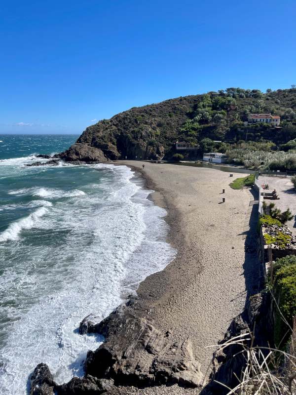 wavy ocean showing the sand and mountain on the side