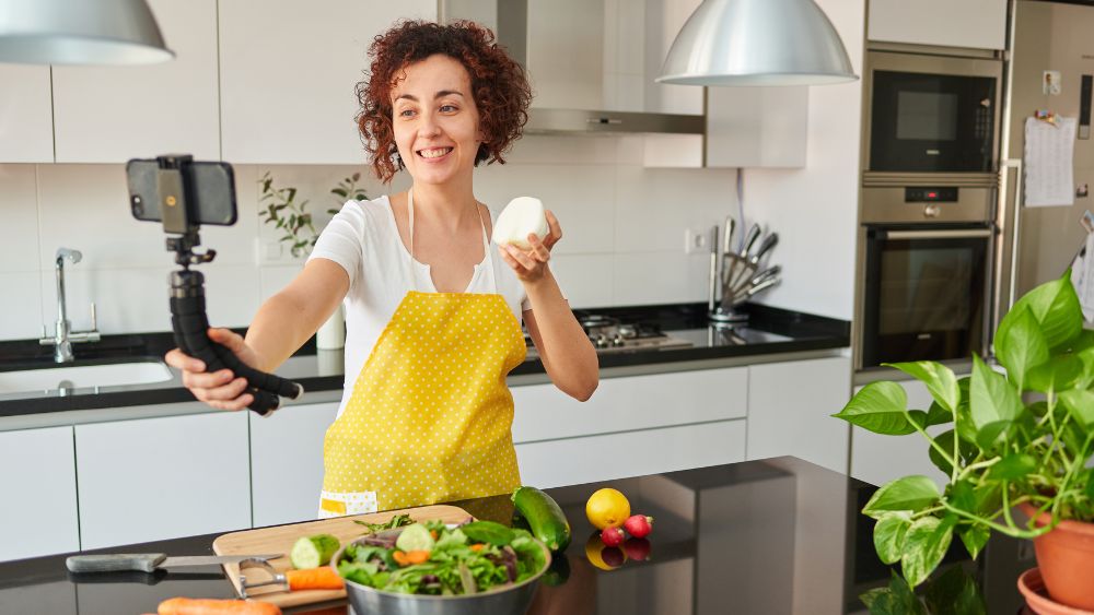 woman preparing vegetable and showing vegetables in front of her phone