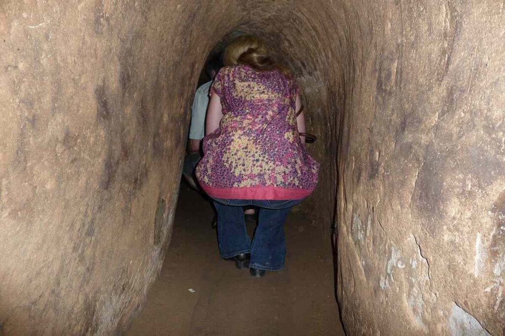 people crawling through narrow passages underground - Underground Attractions