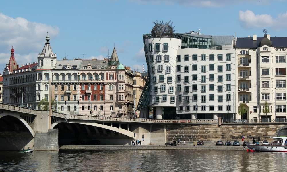 concrete rare shape structure building near the bridge above body of water