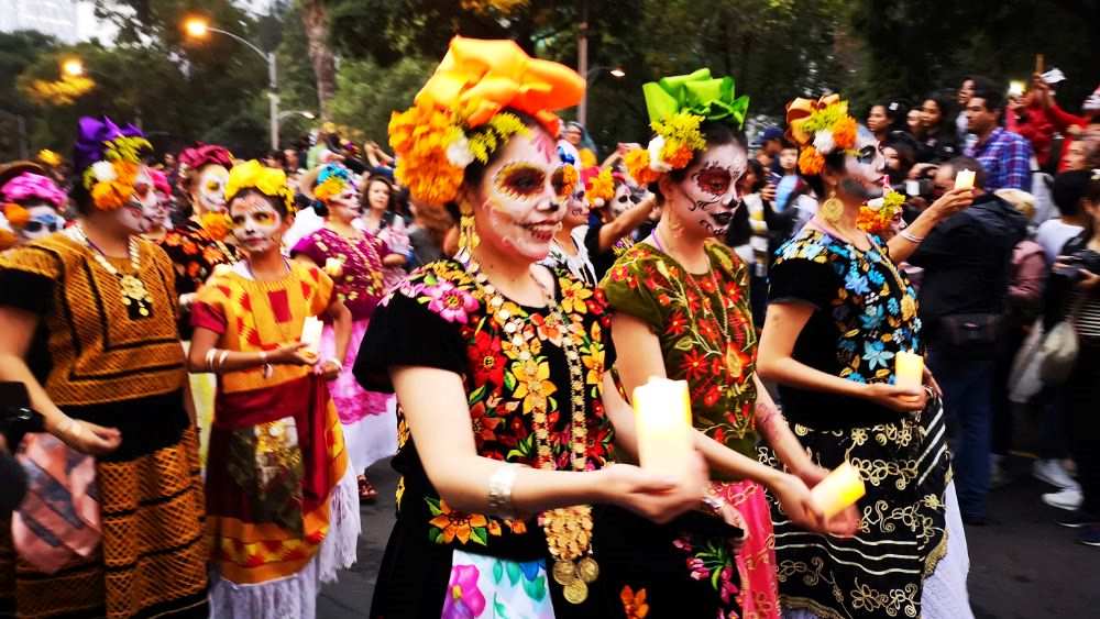 woman in colorful dress and facepaint marching in the street