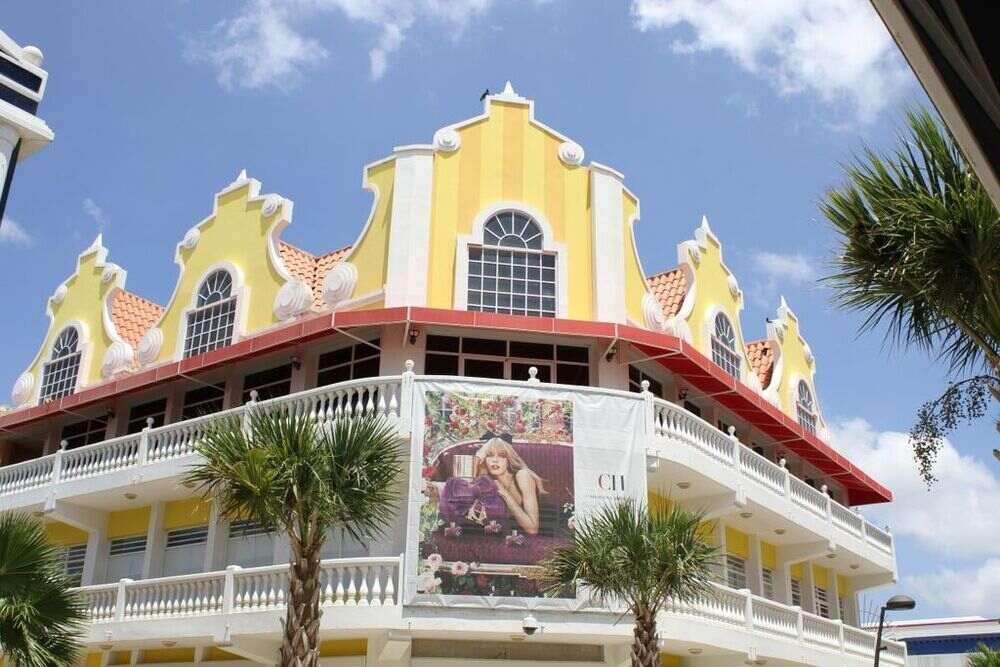 yellow tall building ith banner of a woman in Downtown, Oranjestad