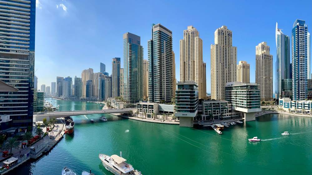 high rise buildings near body of water with boats/yatch sailing