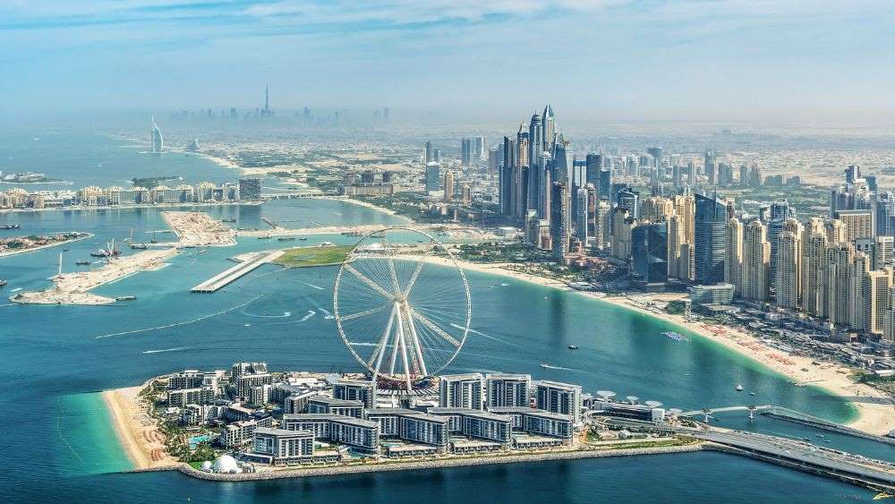 aerial view of the city showing high rise building and ferries wheel in the middle of the island surrounded by body of water