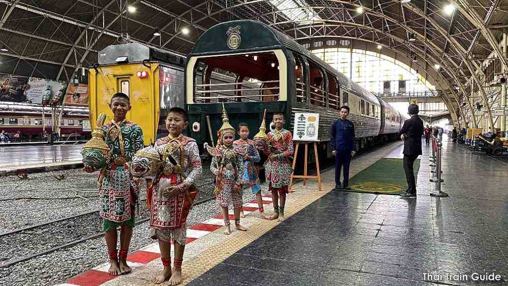 kinds in Thai historical costume in front of a green train