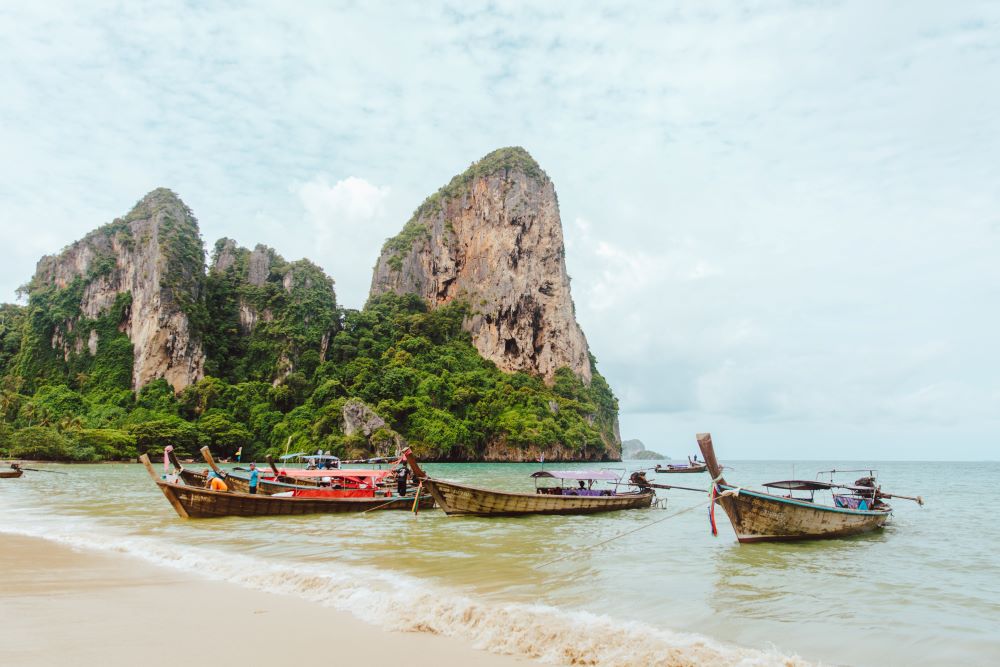 boat in the side of the ocean with rock mountains at the back