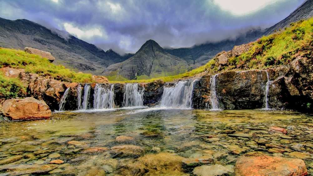 waterfalls surrounded by grass and trees