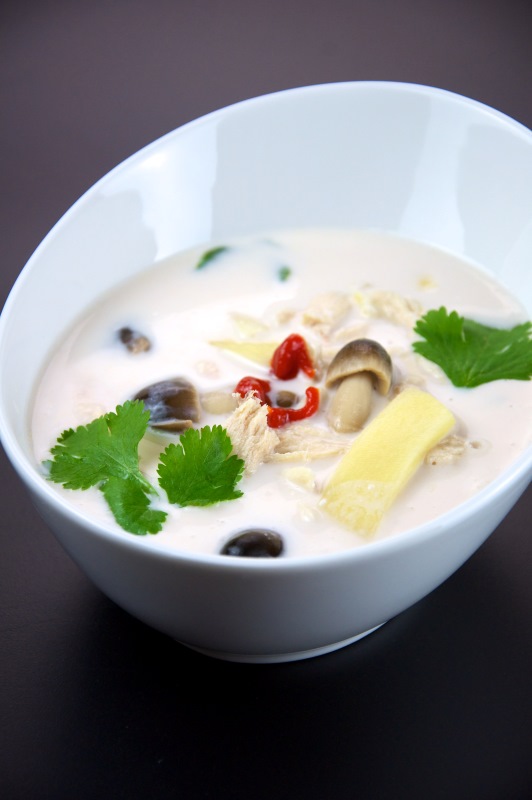 white soup with mushroom and green leaves in white dish - best thai food in thailand
