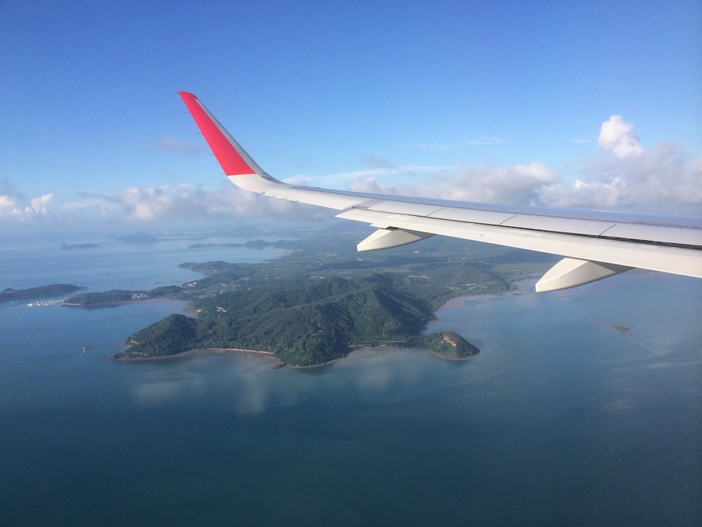 Wing of the airplane with green island surrounded by water