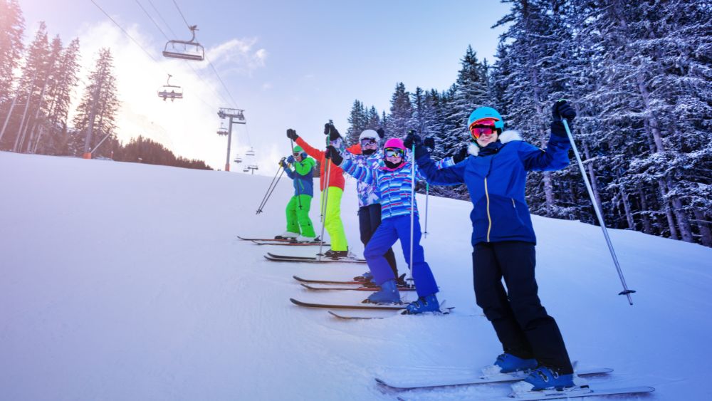 group of kids skiing on top of the french alps surrounded by snow