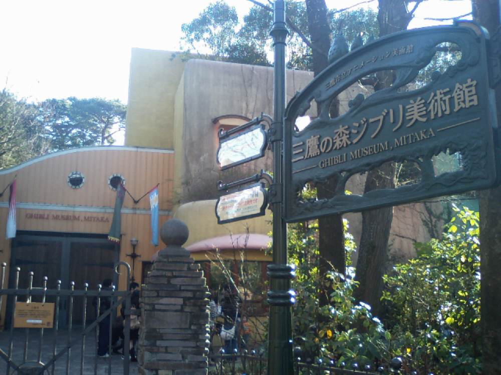 green signage of the Ghibli Museum, beside is a yellow building - best things to do in Tokyo