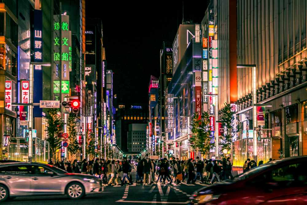 people walking in the street surrounded by buildings during night time - best things to do in Tokyo