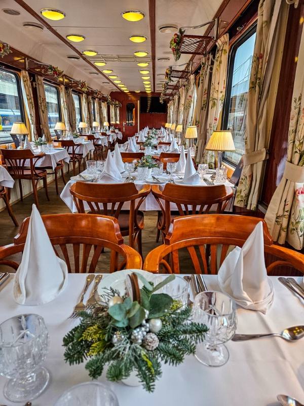 dinning tables and hairs are set inside the train - luxury train rides