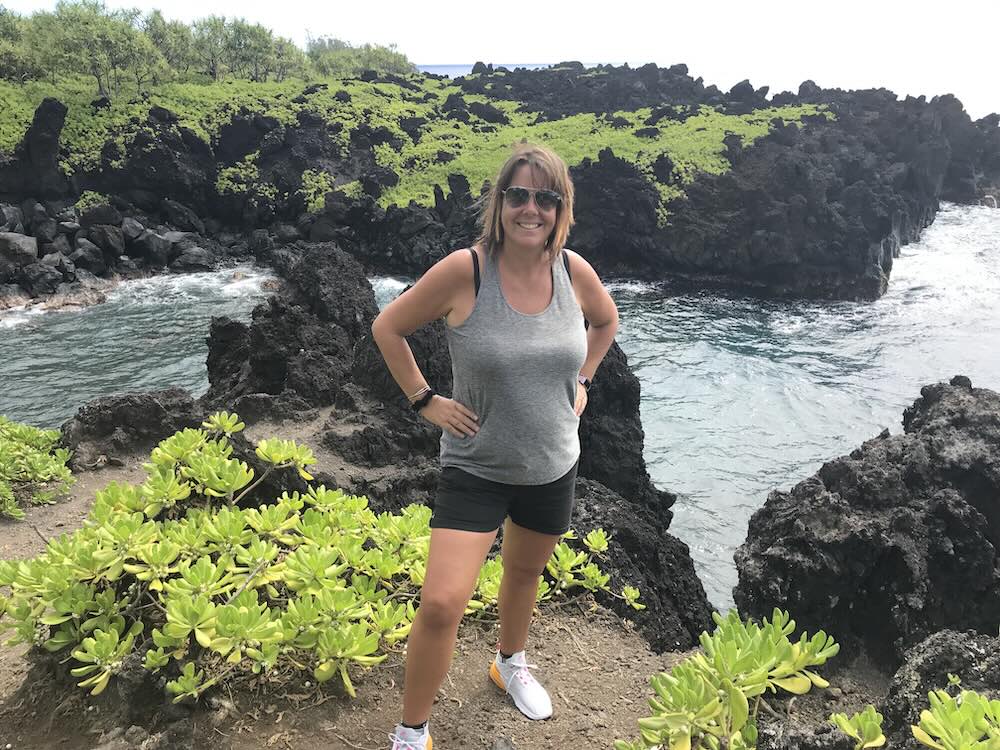 Jo at the Ke Alaloa O Maui Piilani Trail - green foliage against black rocks