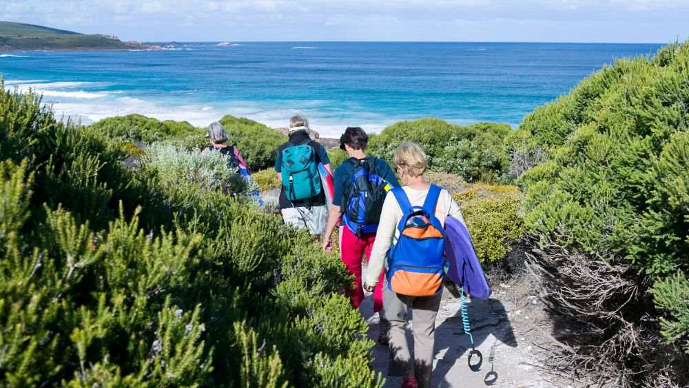 people walking with hiking bag going to the ocean - reasons to visit australia