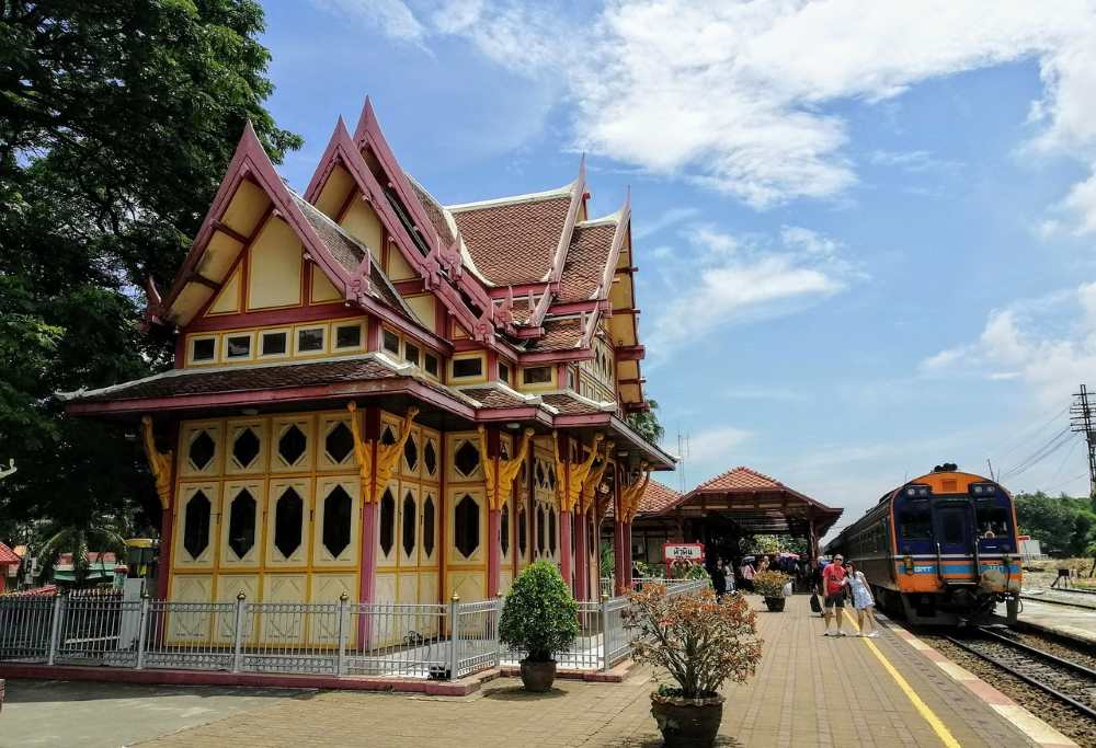 yellow and red structure with couple who are standing  beside is a train - best places to visit in thailand