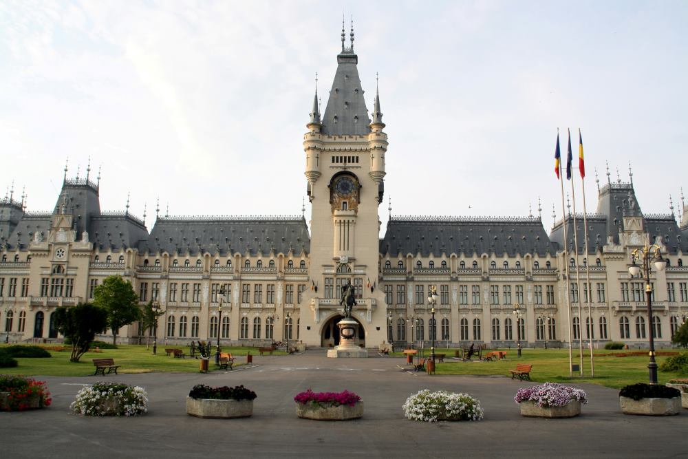 wide structure building with statue in middle front and colorful flowers- romania digital nomad visa