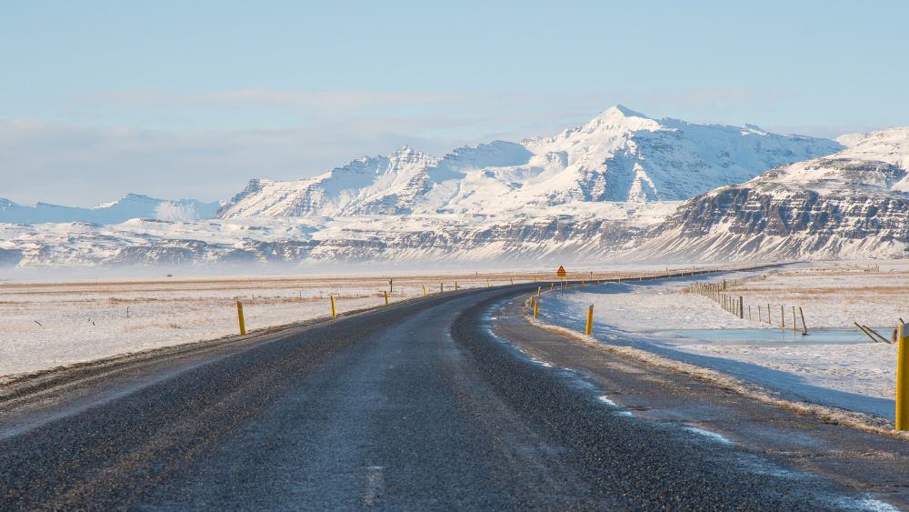 road with snow on the side and in front of snowy mountian
