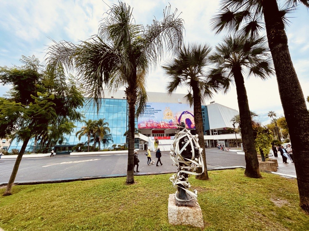 glass building with palm trees in front