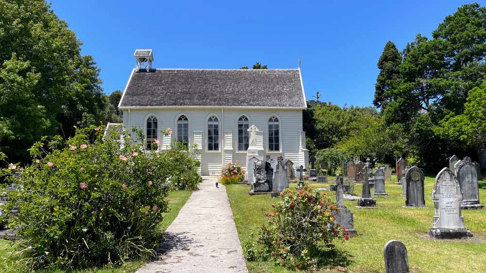 small white church building with tombstones in front