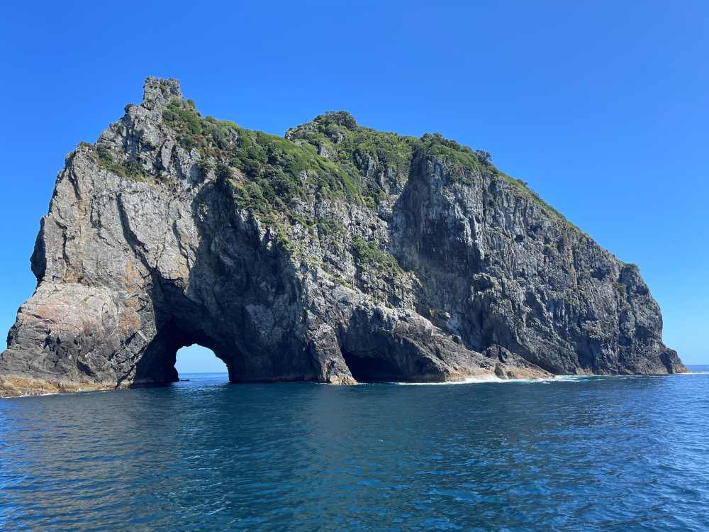 rock formation with hole in the middle of the ocean