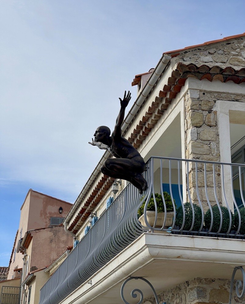 statue of a man sitting on the edge of the veranda