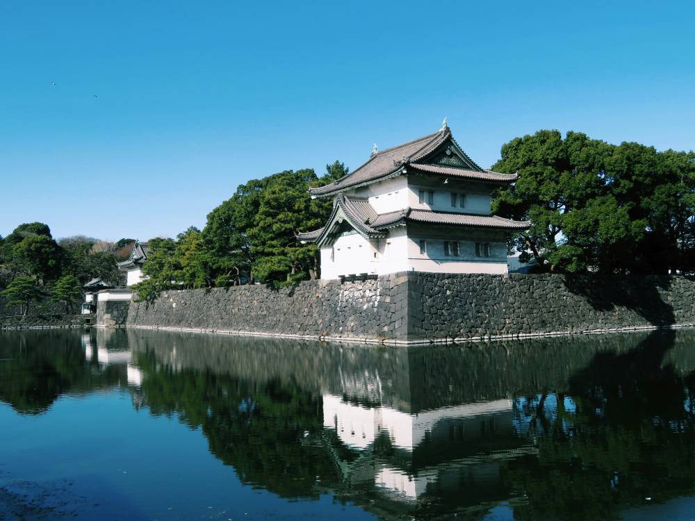 building on top of a body of water surrounded by green trees - best things to do in Tokyo