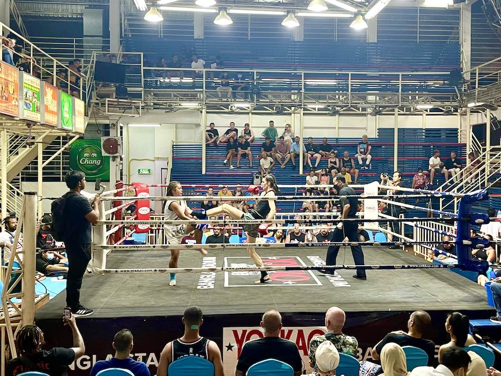 Image of two woman competing muah thai inside an arena