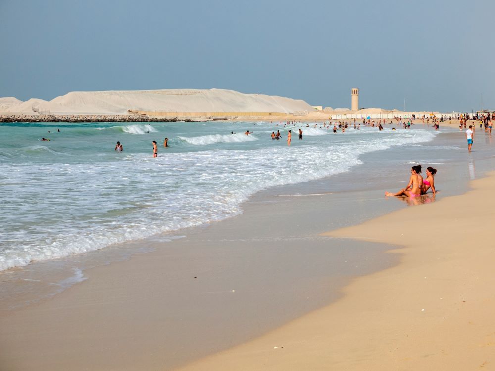 people in the sand and swimming in the beach
